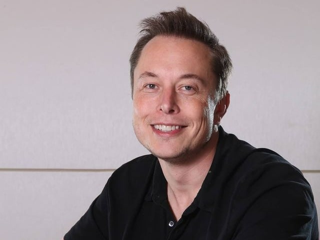 Picture of Elon Musk posing with a smile and Black Tee.